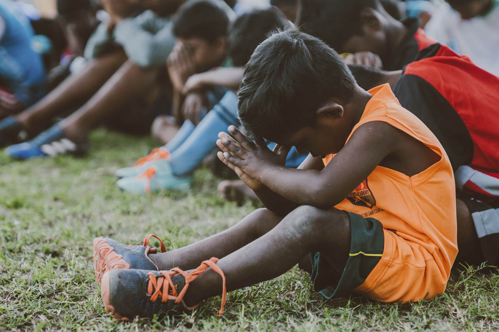 Young boy praying on football field