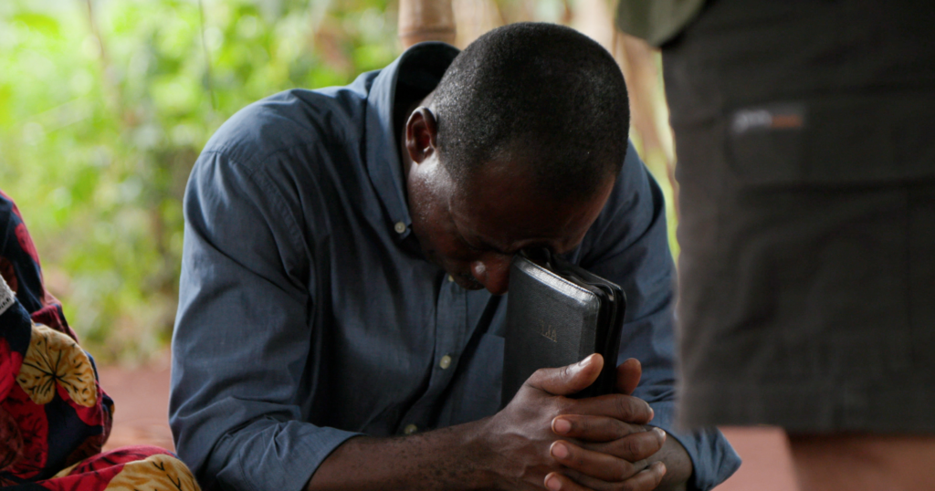 Man praying with hands folder over Bible